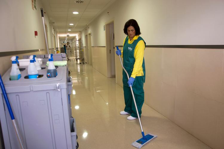 Mujer limpiando el suelo del pasillo de un hospital