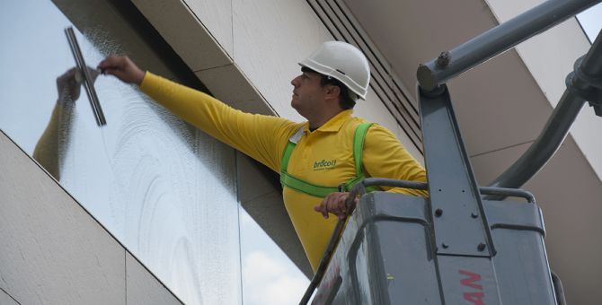 Un operario de Brócoli en una grúa limpiando una ventana de un edificio
